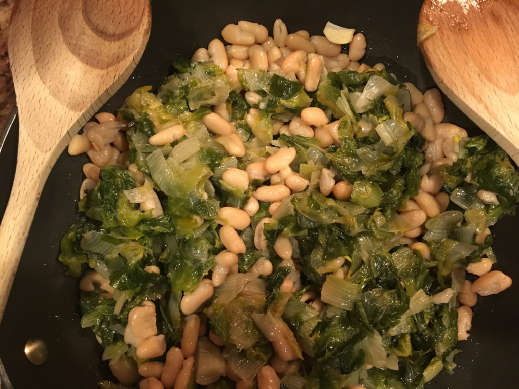 escarole and beans cooking in a l large sauce pan.