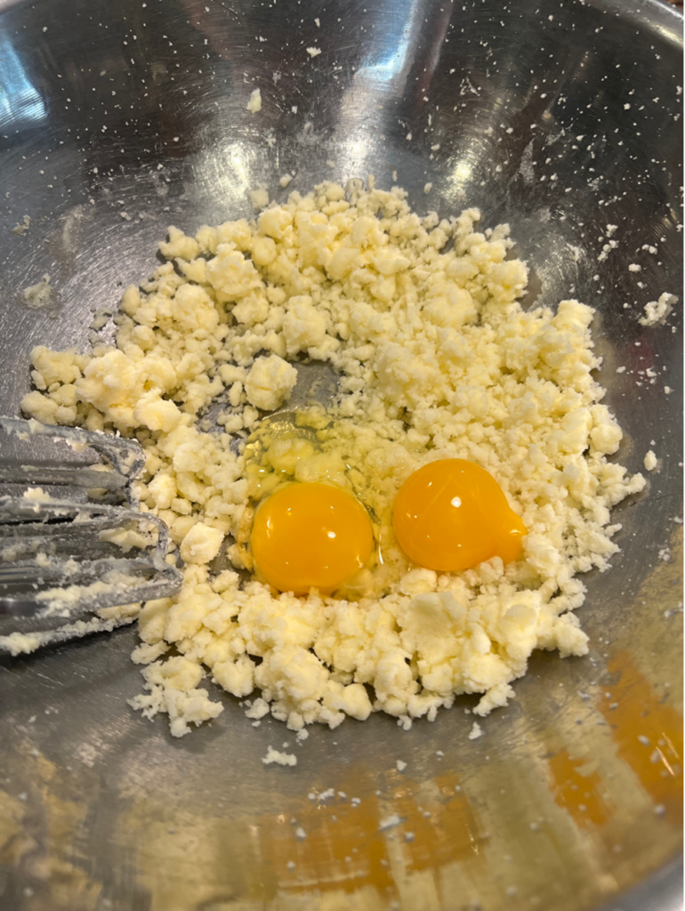 Eggs added to butter and sugar in preparation of the jam crostata. 
