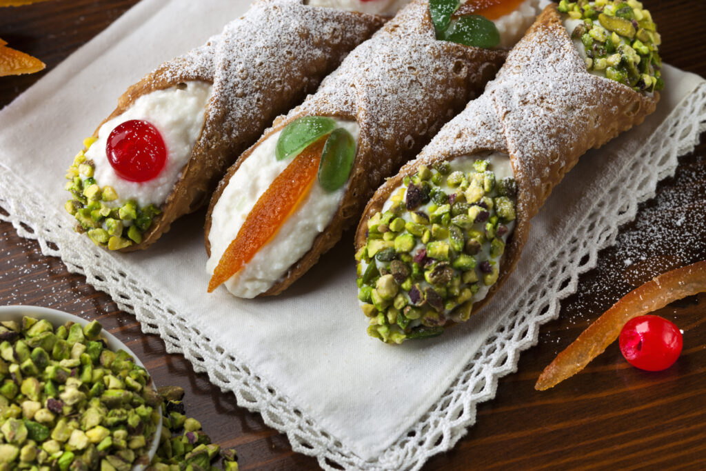 Three sicilian cannoli with ingradients on wooden table