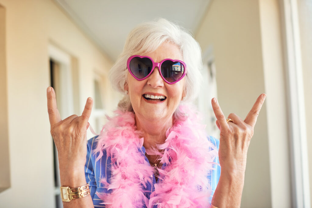 Senior woman making the horn symbol.