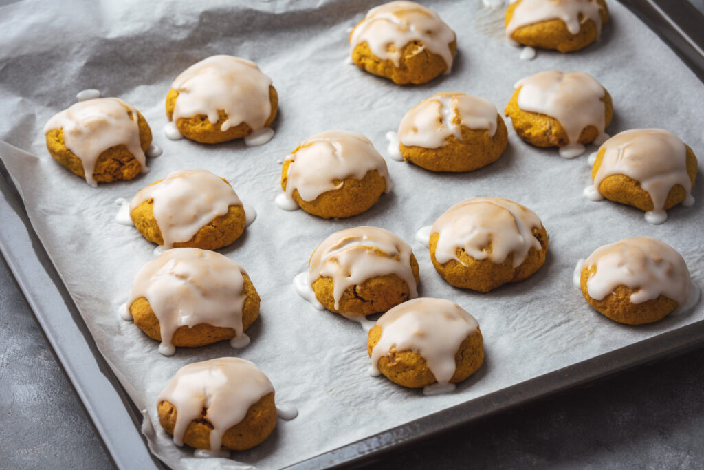 Glazed pumpkin ricotta cookies drying on a cookie sheet. 