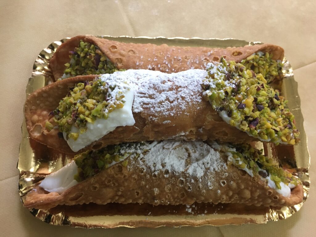 Ricotta filled cannoli on gold tray. 